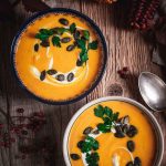 Kürbissuppe in zwei Schüsseln auf einem Holztisch