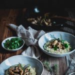 Zwei Teller Risotto mit Pilzen auf einem Holztisch