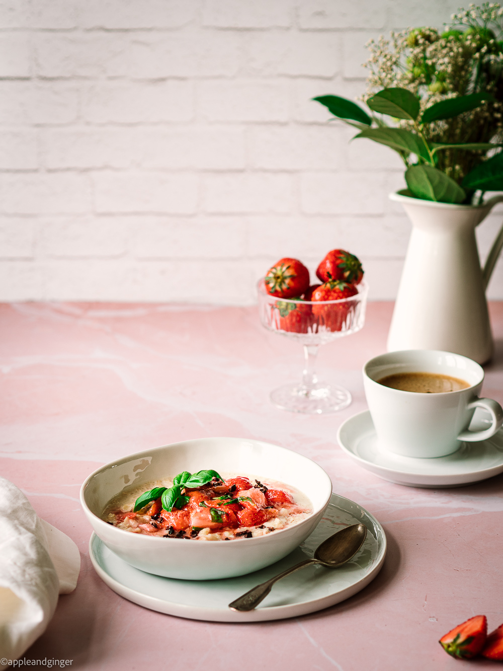 Milchreis mit Erdbeerlompott auf einem rosa Marmor Untergrund mit Kaffeetasse