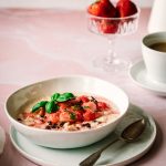 Milchreis mit Erdbeerlompott auf einem rosa Marmor Untergrund mit Kaffeetasse